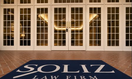 Front entrance of Soliz Law Firm's Houston office, featuring glass French doors and a navy welcome mat with the firm's logo